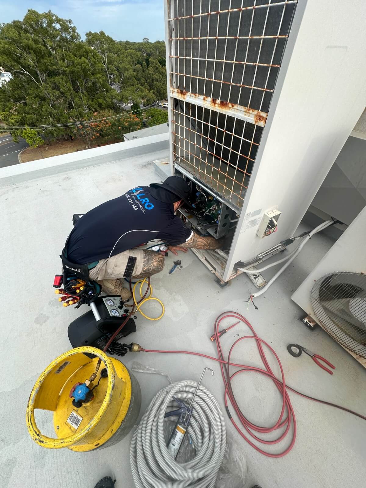 Alro Air technician performing refrigerant recovery using manifold gauges and recovery unit on a VRF air conditioning system in Gold Coast.