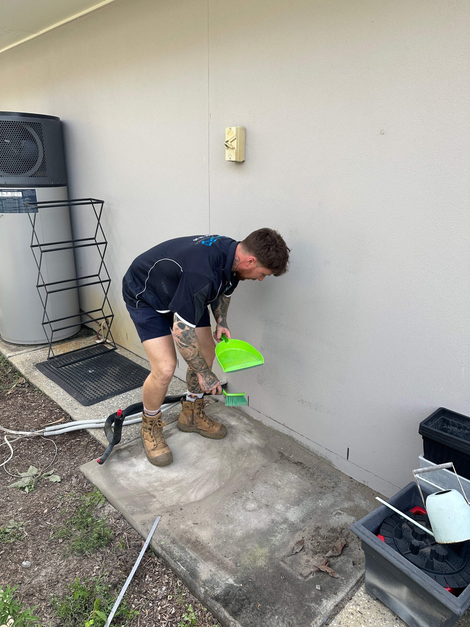 Technician cleaning up slab in preparation for replacement ducted air conditioner installation.