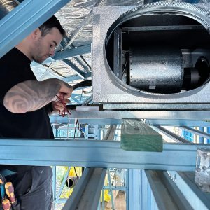 ⁠Technician performing electrical rough-in wiring on a ducted air conditioning indoor fan coil unit inside a steel frame house